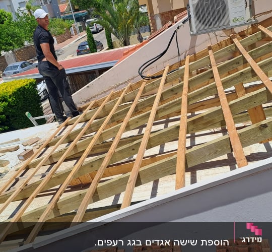 עבודת בניית גג עם קורות עץ ואדם על הגג